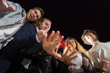 Group of friends having fun together outdoor in a night and light behind them