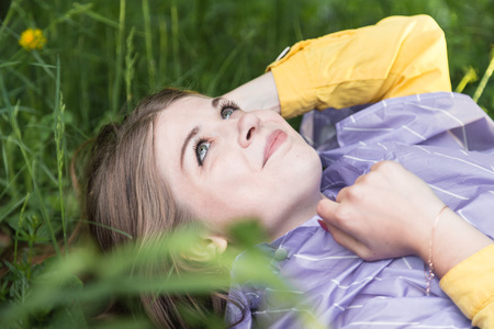 Beautiful young woman on the grass in the park at a summer or a spring timeの写真素材