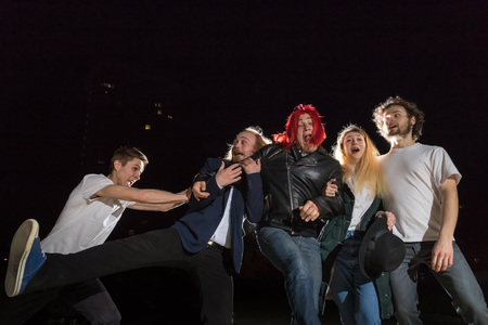 Group of friends having fun together outdoor in a night and light behind themの写真素材