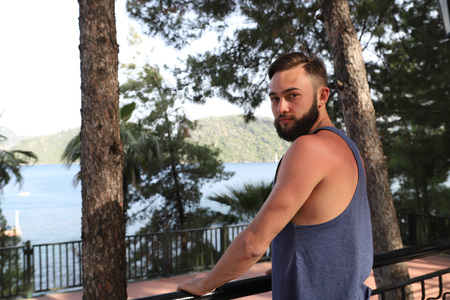 Young man with black hair and beard sitting in a restaurant in the Park in a summer evening and...