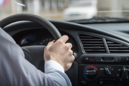 Man hands holding steering wheel while driving car. Close up pictureの写真素材