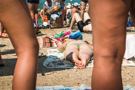 Russia, Sol-Iletsk - August 03, 2016: Woman sunbathing in a summer evening on the city beach and other people arroundのeditorial素材