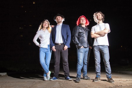 Group of friends having fun together outdoor in a night and light behind themの写真素材