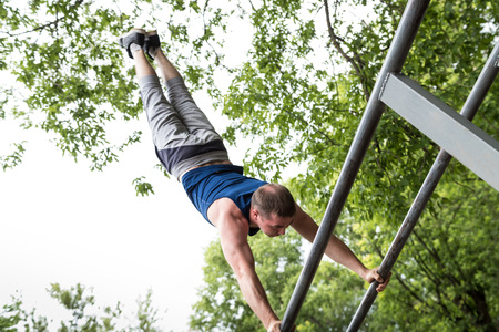 Attractive fitness man doing exercises in a summer park