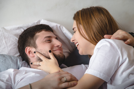 Lovely couple have fun, rest and relax on the bed in the bedroom. Lifestyle concept