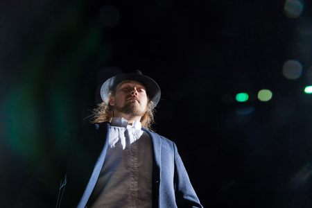Portrait of young man outdoors with black background and light behind himの写真素材