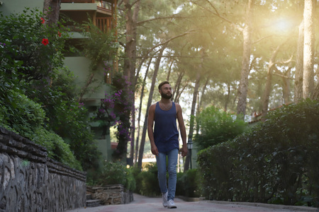 Young man with black hair and beard in the Park in a summer evening and green trees arroundの写真素材