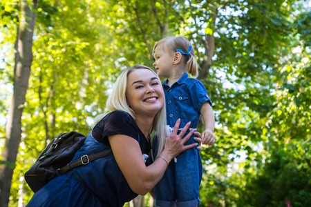 Cute blonde woman and her daughter in the park. Family with happy emotion. Horizontal portrait...