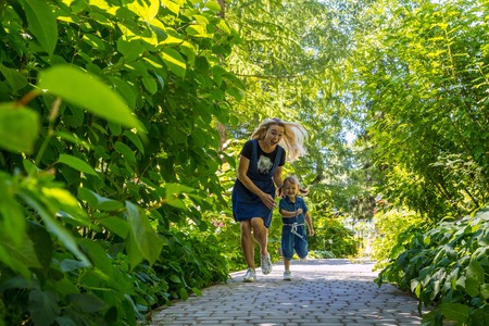 Cute blonde woman and her daughter in the park. Family with happy emotion. Horizontal portrait little girl and her mom walking outdoor togetherの写真素材