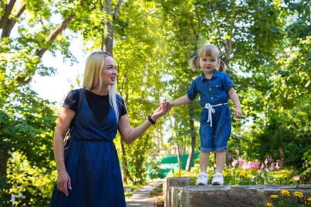 Cute blonde woman and her daughter in the park. Family with happy emotion. Horizontal portrait...
