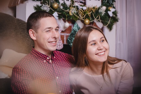 Young couple celebrating Christmas in the room decorated for Mary Christmas and New year