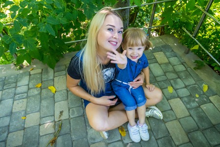 Cute blonde woman and her daughter in the park. Family with happy emotion. Horizontal portrait...
