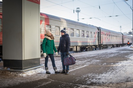 Couple at railway station near train in a winter time and snow aroundの写真素材