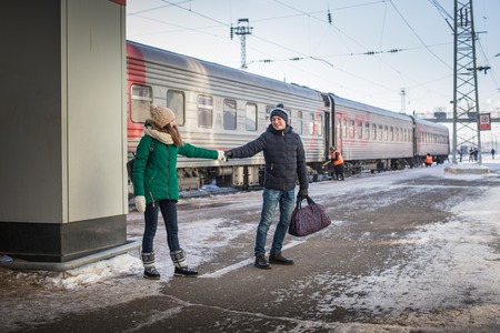 Couple at railway station near train in a winter time and snow aroundの写真素材