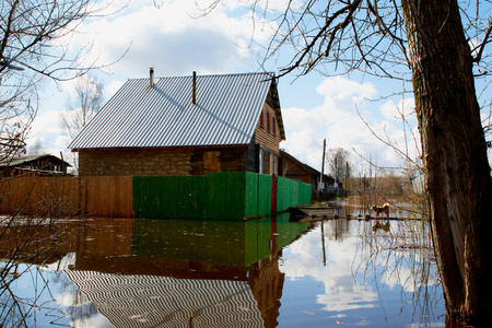 Floods in the spring and a village house in the water in Russia in a cloudy dayの写真素材