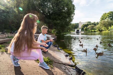 Kirov, Russia - August 21, 2018: Happy family feeding ducks on the lake in the Park. Mom, dad, son and daughter during a walk in the summer dayのeditorial素材