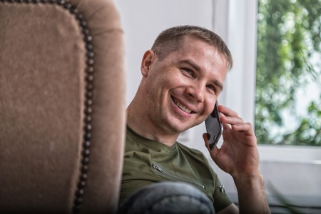 Relaxed young man in shirt resting in living roomの写真素材