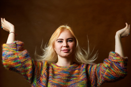 Portrait of the beautiful sexual girl. Blonde young woman in motley sweater. Playing with hair. Picture in low keyの写真素材