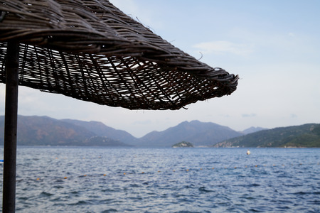 Sea, mountain and braided umbrella in a nice summer dayの写真素材