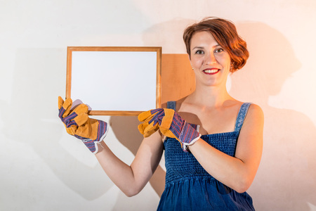 Sexy cute girl who is builder, painter, worker being in a renovated room. Hands in gloves and frameの写真素材