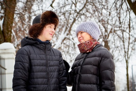 Mother and adult son walking in city park in a winterの写真素材