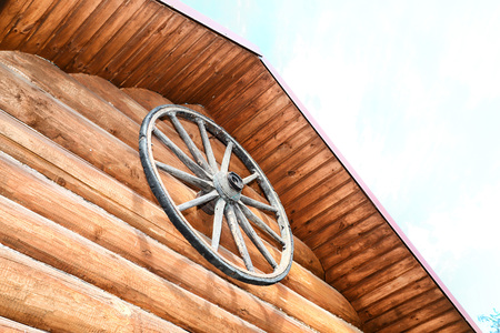 Wooden wheel on wooden wall in rustic houme. Old rural concept