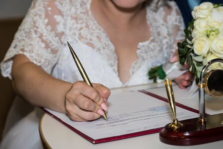 Kirov, Russia - July 27, 2018: Bride and groom signing marriage wedding certificate at registry officeのeditorial素材
