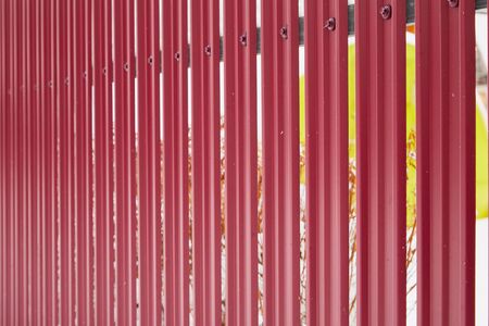 Aluminum fence. Corrugated metal profiled panel. Background of red metal siding, corrugated iron sheet for exterior decorationのeditorial素材