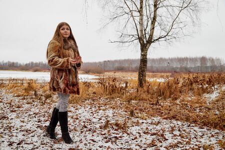 Sad girl in the brown coat waiting for a date in autumn in a parkのeditorial素材