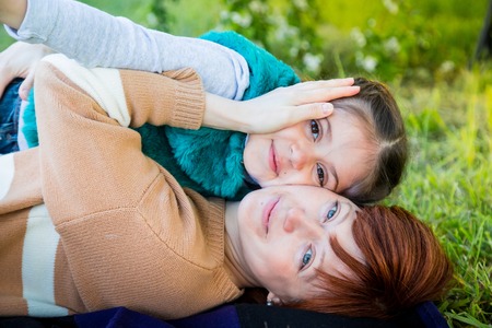 Portrait of mother and daughter having fun near blossom apple trees in a spring parkの写真素材