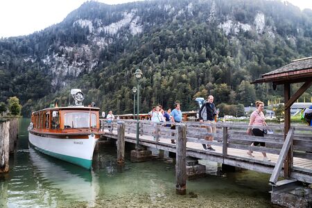 Germany, Koenigssee - September 16, 2018: Beautiful lake and wooden pier for ships with tourists in Koenigssee in Germany in summer dayのeditorial素材