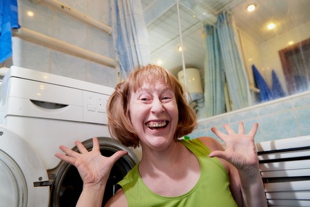 Housewife near washing machine in the bath room and she is happy with the clean laundry. The concept of homework and Laundry at homeの写真素材