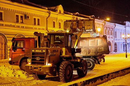 Kirov, Russia - December, 28: Tractor and truck cleaning snow at night on the streets of Kirov in...