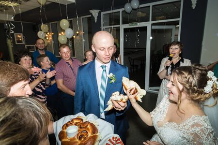 Kirov, Russia - July 27, 2018: Bride and groom in a restaurant with guests. Russian traditional meeting of the newlyweds by their parents and treating them loafのeditorial素材