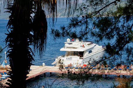 Marmaris, Turkey - May 23, 2018: Branches of trees and view of sea, mountain and ship through them. Holiday conceptのeditorial素材