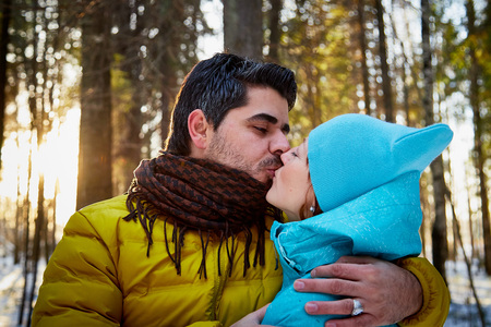 Happy loving couple in snowy winter forest. Ordinary Russian girl and handsome turkish man having fun and hug. Active winter vacations outdoorの写真素材