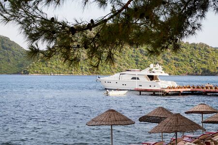 Marmaris, Turkey - May 25, 2018: Branches of trees and view of sea, mountain and ship through them. Holiday conceptのeditorial素材