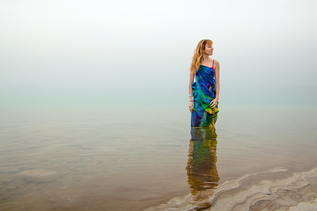 Nice woman stands in water of Dead Sea in Jordan and fog arroundの写真素材