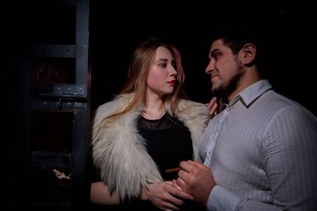 Kirov, Russia - December 19, 2019: Girl and boy near the bars in a dark room. Date mistress with a prisoner in prison. Photo shoot in the style of gangsters from Chicagoのeditorial素材