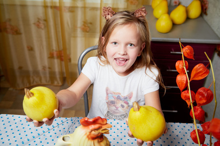 A little girl sitting at a table with yellow zucchini. Autumn harvest conceptの写真素材