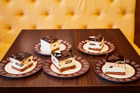 Tasty chocolate cake on the table in restaurant. Small pieces of delicious dessert on brown platesの写真素材