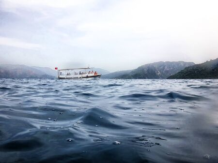 Marmaris, Turkey - May 21, 2018: Sea surface, waves, mountain coast in the distance and ship. View and shooting from water in a summer dayのeditorial素材