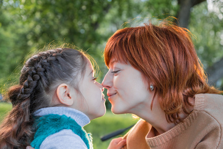 Portrait of mother and daughter having fun near blossom apple trees in a spring parkの写真素材