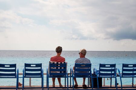 Nice, France - September 23, 2018: Promenade near the sea, big bench and tourist sitting on it and looking at the sea in Nice in France in a good dayのeditorial素材