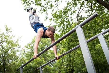 Attractive fitness man doing exercises in a summer park