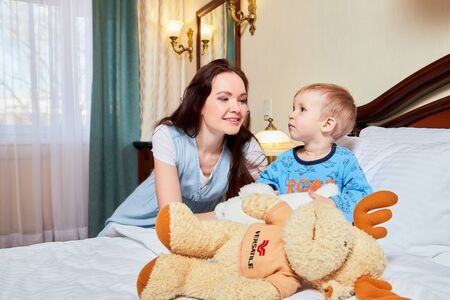Kirov, Russia - March 02, 2019: Mother and son resting in the hotel room on the bed. Family travelers togetherのeditorial素材