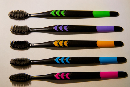 Colorful toothbrush with black bristles on white background. Five things on paper