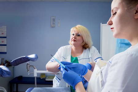 Experienced doctor fat woman and aspiring young doctor discussing the medical problems in the...