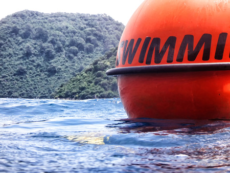 Sea surface with buoys with words No swimming and mountains in the distance. View and shooting from...