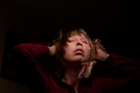 Portrait of ugly but sweet girl with chubby cheeks and dark background. Photo shoot of middle-aged women in the Studio with interesting backlightの写真素材